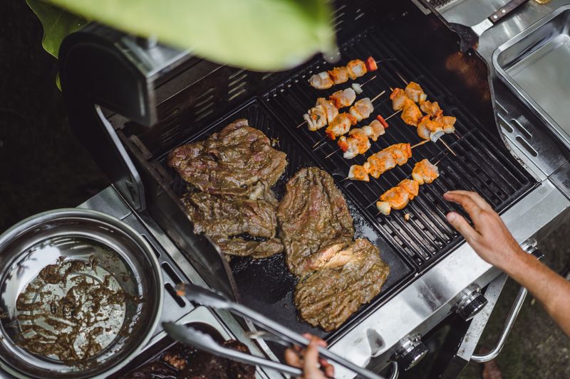 man-tattoos-makes-barbecue-grill-meat-outdoors