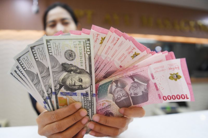 Petugas menghitung mata uang Rupiah dan Dolar AS