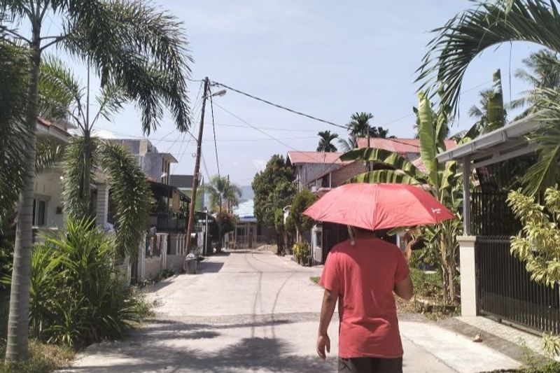 Seorang warga saat berjalan menggunakan payung untuk meminimalisir teriknya paparan sinar matahari