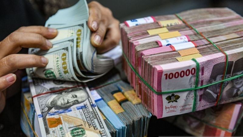 Petugas menghitung uang pecahan dolar AS dan rupiah 