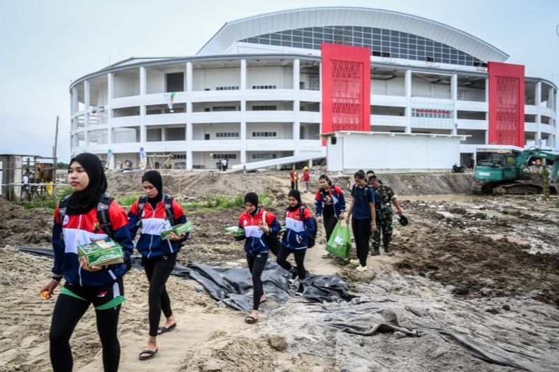 Sejumlah pemain voli PON XXI Aceh-Sumut melewati jalan berlumpur di GOR Bola Voli Indoor Sumut