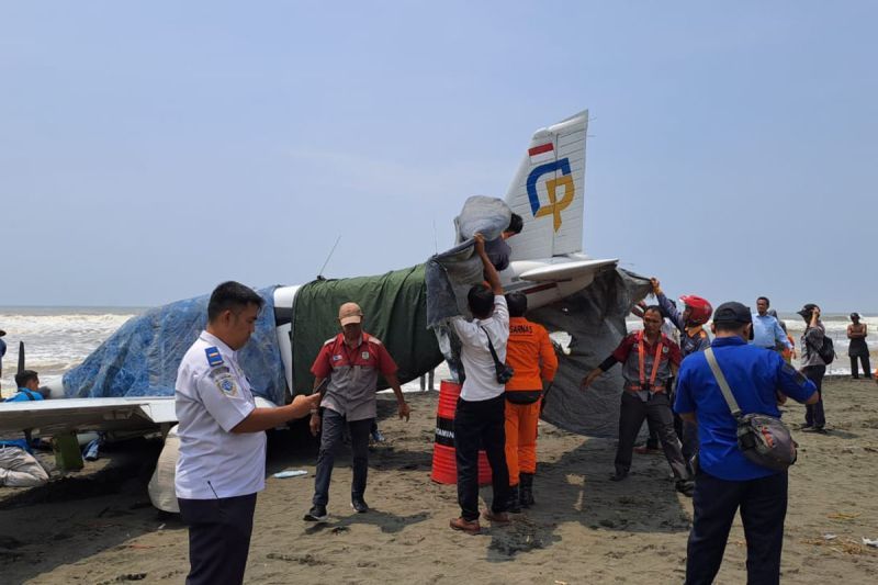 Petugas gabungan menutup badan pesawat latih yang mendarat darurat di Pantai Cemara Sewu