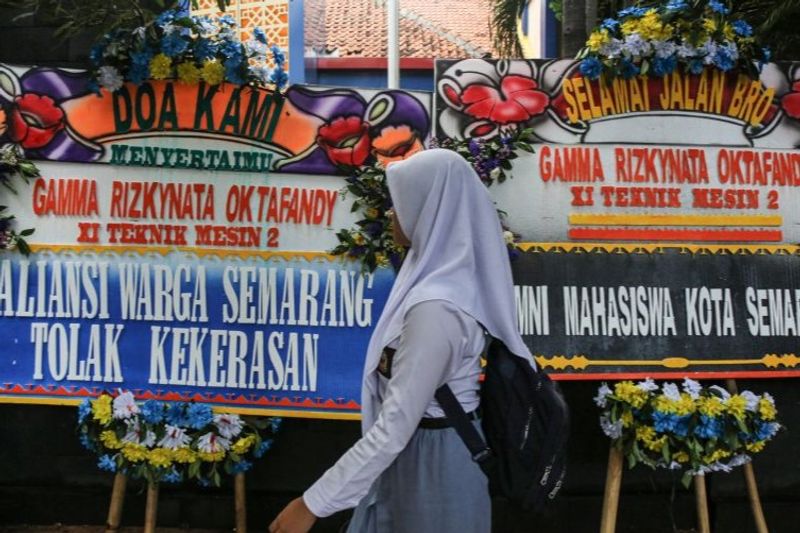 Seorang siswa melintasi karangan bunga untuk kepada siswa korban penembakan oleh oknum polisi