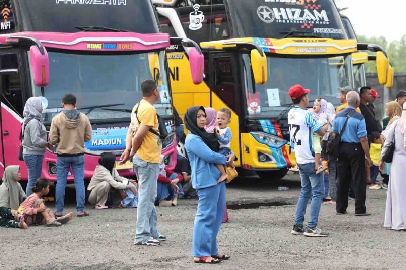 Sejumlah calon penumpang bus berdiri di depan bus