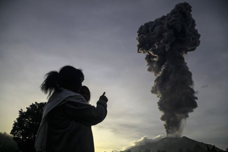 Seorang warga melihat erupsi dari kawah Gunung Ibu