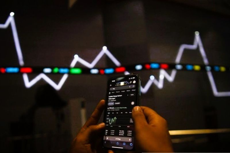 Karyawan melintas di dekat monitor pergerakan Indeks Harga Saham Gabungan (IHSG)