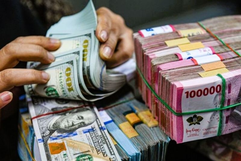 Petugas menghitung uang pecahan dolar AS dan rupiah