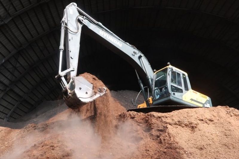 Pekerja mengoperasikan ekskavator mencampur biomassa dengan batu bara di kawasan PLTU Jeranjang