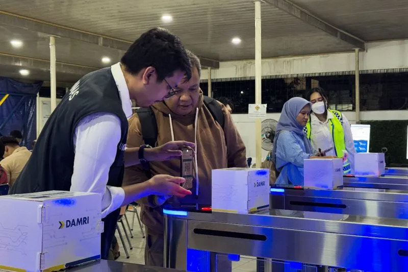 Petugas Damri membantu calon penumpang memindai tiket di pintu masuk