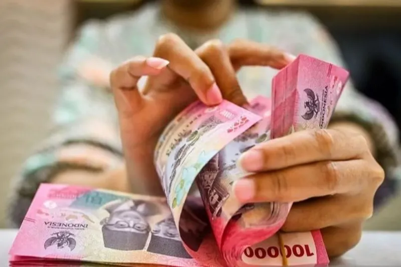 Petugas menghitung uang rupiah di gerai penukaran mata uang asing di Jakarta