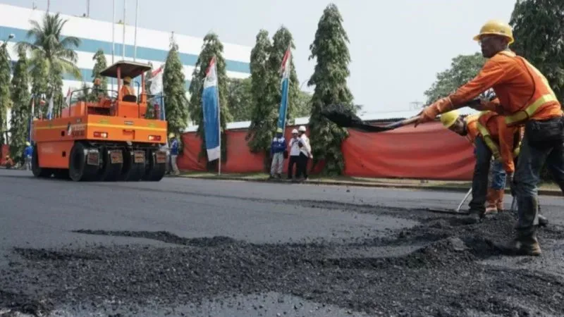 Pekerja melakukan pengaspalan jalan yang menggunakan aspal berbahan baku plastik 