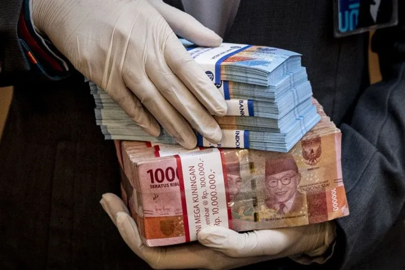 Karyawan memegang uang di BNI KC Mega Kuningan
