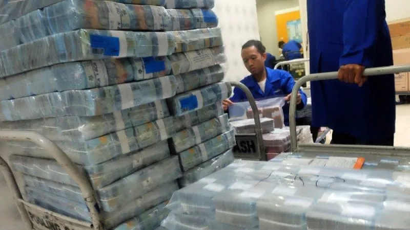 Petugas memindahkan tumpukan uang tunai di Pooling Cash Plaza Mandiri