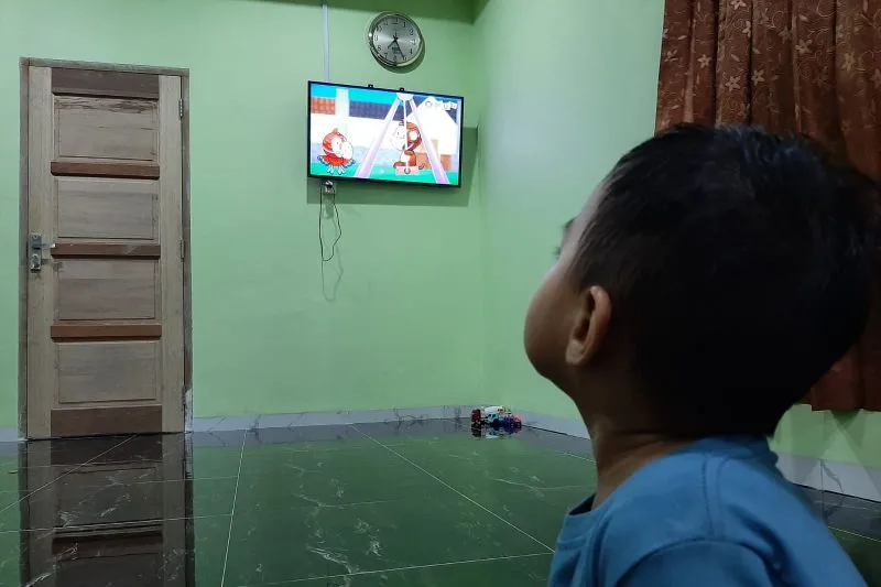Anak sedang menonton televisi di rtumah