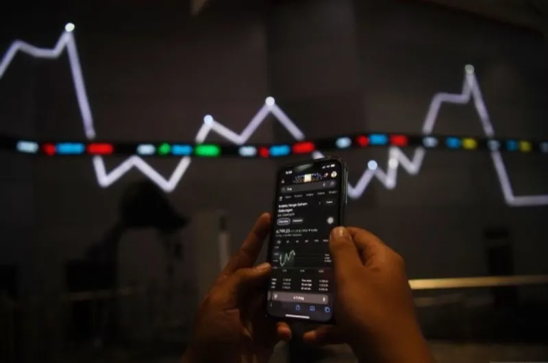 Karyawan melintas di dekat monitor pergerakan Indeks Harga Saham Gabungan (IHSG)