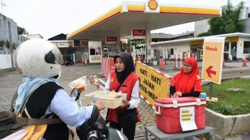 Pengendara motor membeli makanan yang dijual petugas SPBU di depan SPBU Shell