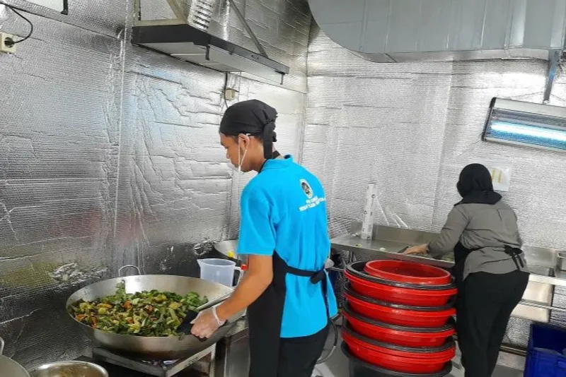 Asisten koki SPPG sedang menumis sayuran untuk para siswa penerima Makan Bergizi Gratis 