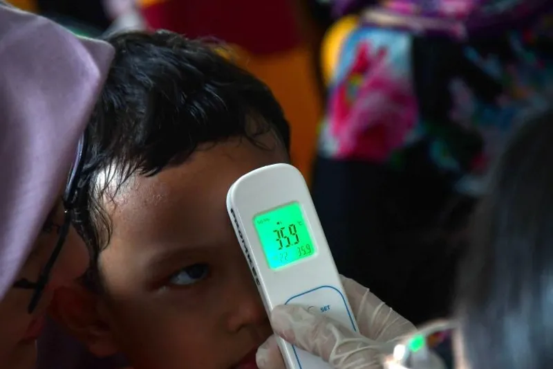 Petugas kesehatan mengukur suhu tubuh anak balita
