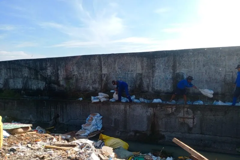 Petugas Sudin memasang karung menyumpal air laut yang merembes di tanggul jakarta