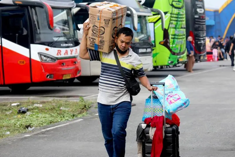 Seorang penumpang kendaraan bus membawa barang bawaan saat tiba di terminal bus