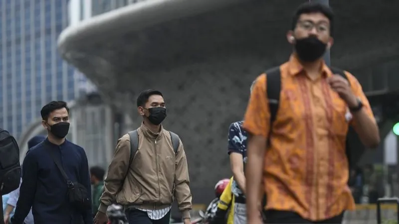 Warga menggunakan masker saat berjalan di Jakarta
