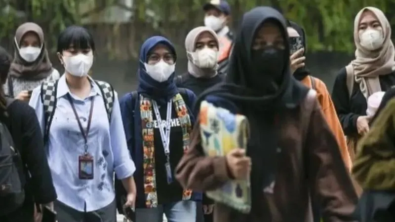 Warga menggunakan masker saat berjalan di Jakarta