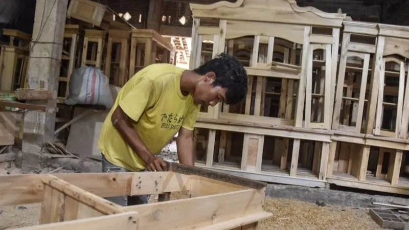 Pekerja menyelesaikan pembuatan furnitur di rumah produksi Tiga Putra