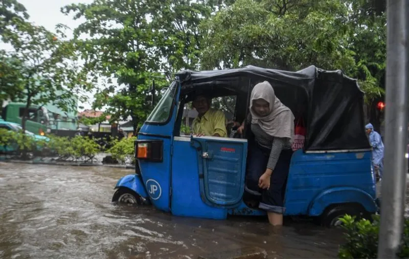 Warga turun dari bajaj saat banjir di kawasan Sunter