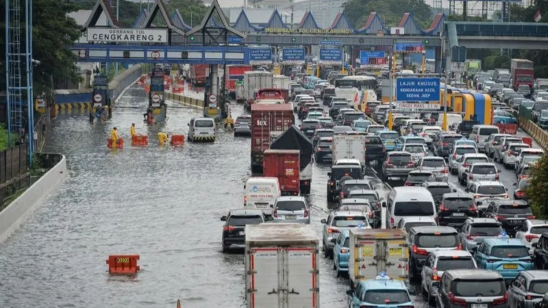 Petugas memasang pembatas jalan di gerbang tol yang terendam banjir di Jalan Tol Sedyatmo