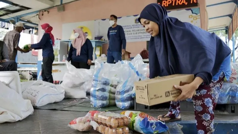 Warga mengambil belanjaan paket bahan pangan bersubsidi di Jakarta