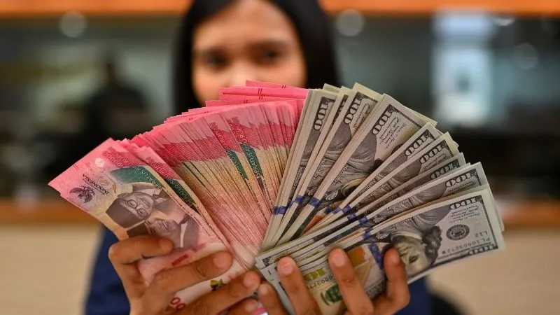 Karyawan memperlihatkan uang pecahan rupiah dan dolar Amerika Serikat