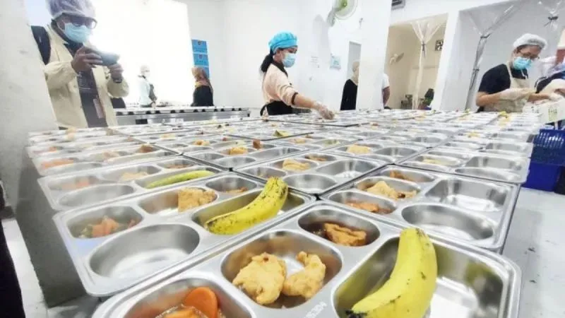 Petugas tengah memorsi menu Makan Bergizi Gratis (MBG) 