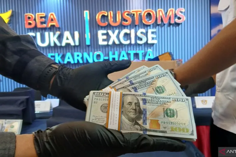 Petugas menunjukan mata uang asing