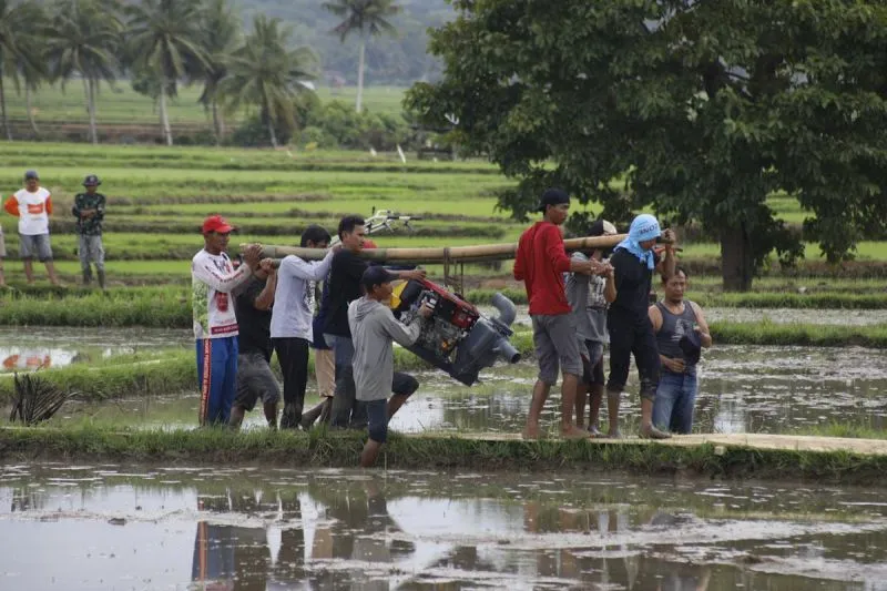 Petani menggotong pompa air menuju areal persawahan 