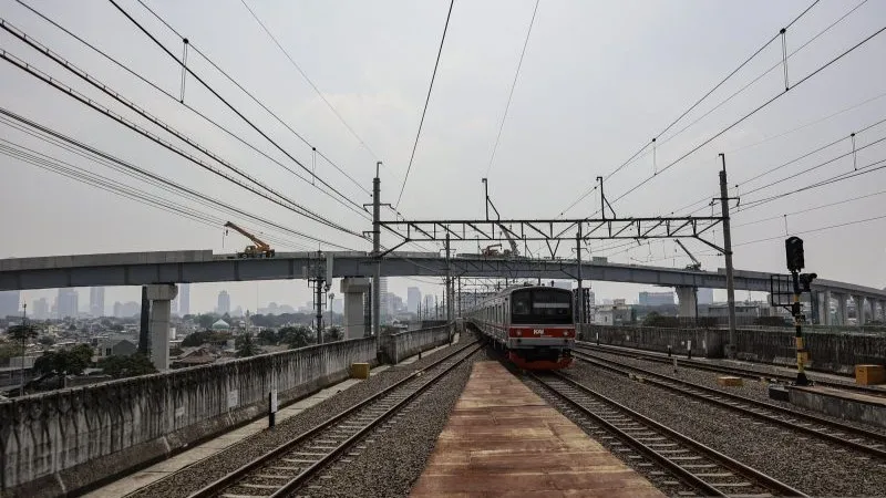 Rangkaian kereta Commuterline melintas di bawah proyek pembangunan jalur LRT Jakarta Fase