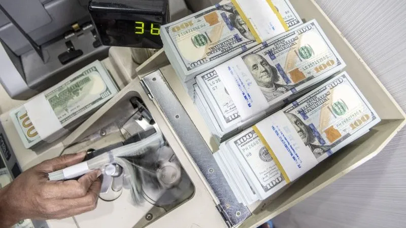 Petugas menghitung uang dolar AS
