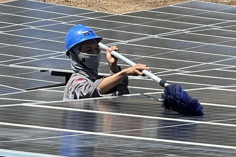 pekerja membersihkan panel surya Pembangkit Listrik Tenaga Surya (PLTS) 