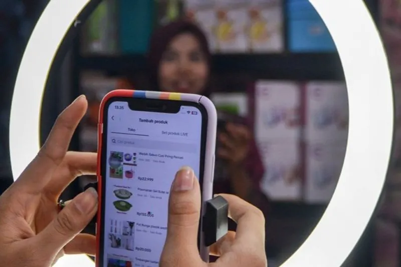 Seorang pedagang memilih katalog untuk dijual melalui siaran langsung secara daring