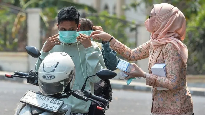 Pengendara sepeda motor memakai masker yang dibagikan 