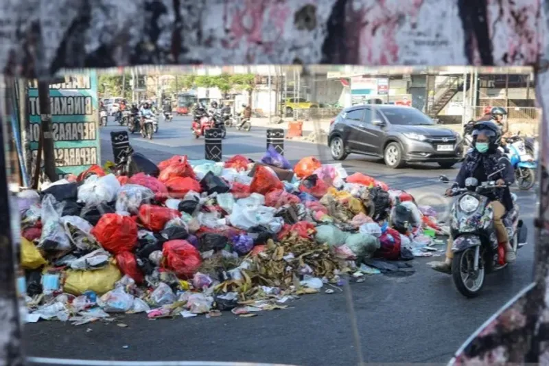 Pengendara sepeda motor melintas di dekat tumpukan sampah di Gowa