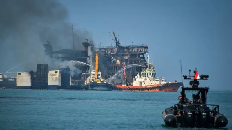 Kapal tunda menyemprotkan air ke arah KMP Batumandi yang terbakar