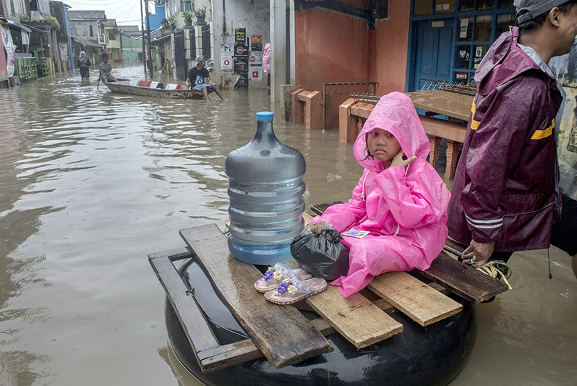 Seorang anak menaiki ban saat melintasi banjir di kawasan Baleendah, Kabupaten Bandung, Jawa Barat, Senin (13/11).